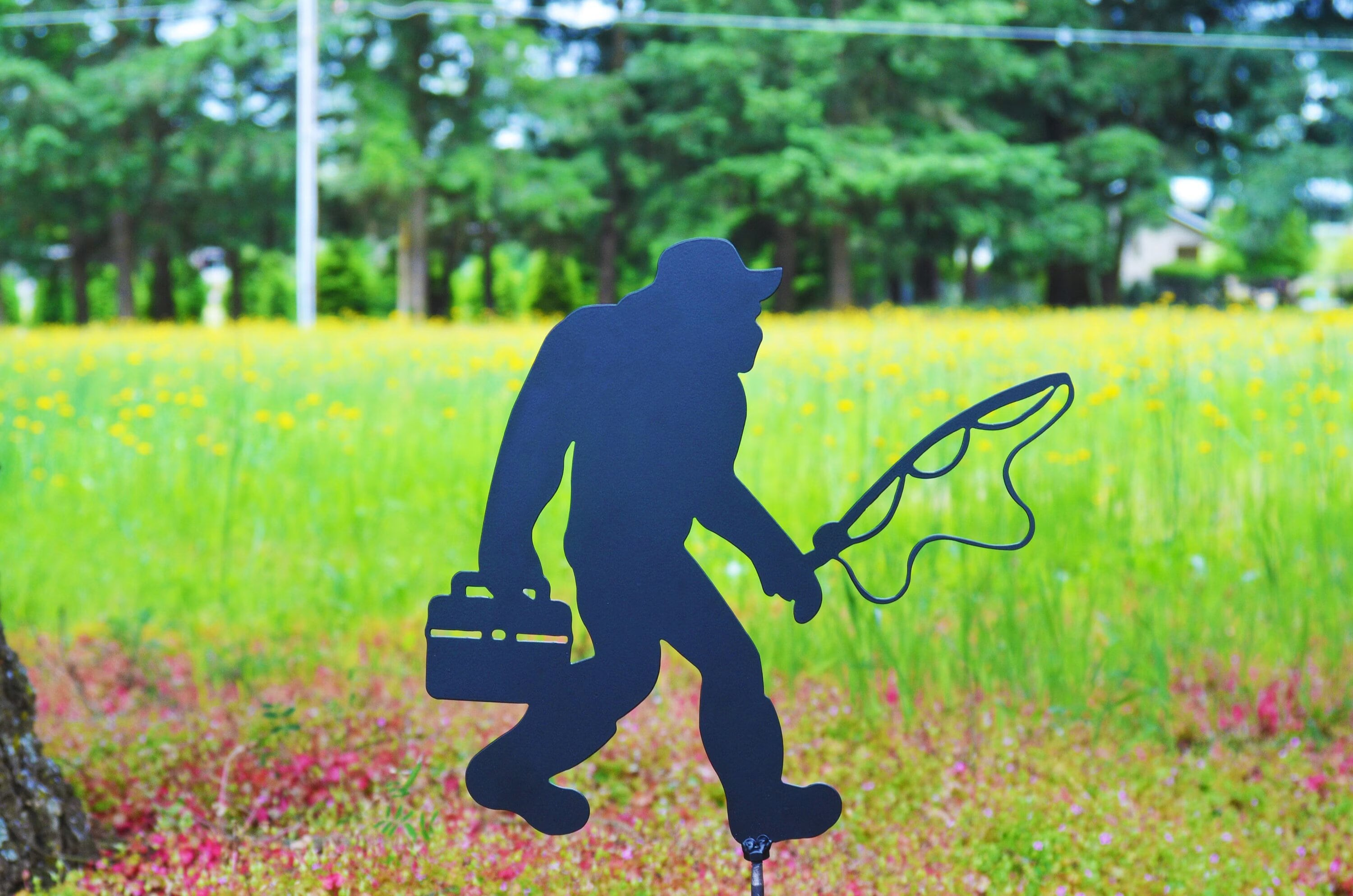 Bigfoot fishing with a fishing pole and tackle box and fishing bucket hat and weighter fly fishing shoes 